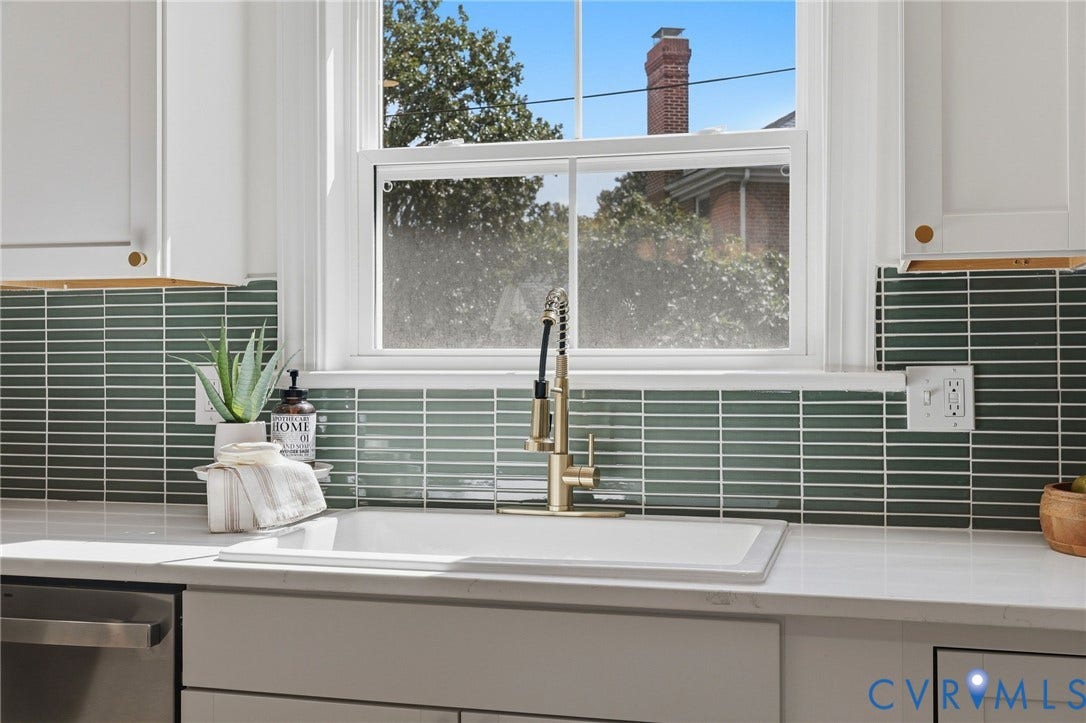 White farmhouse sink with a gold-finish faucet, quartz countertop, and green horizontal tile backsplash