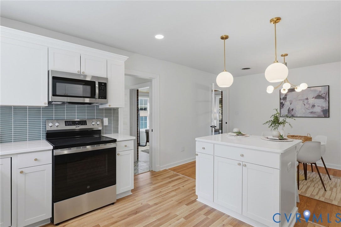 White shaker cabinetry, stainless steel appliances, light wood-finish flooring, white quartz countertops, and a white kitchen island