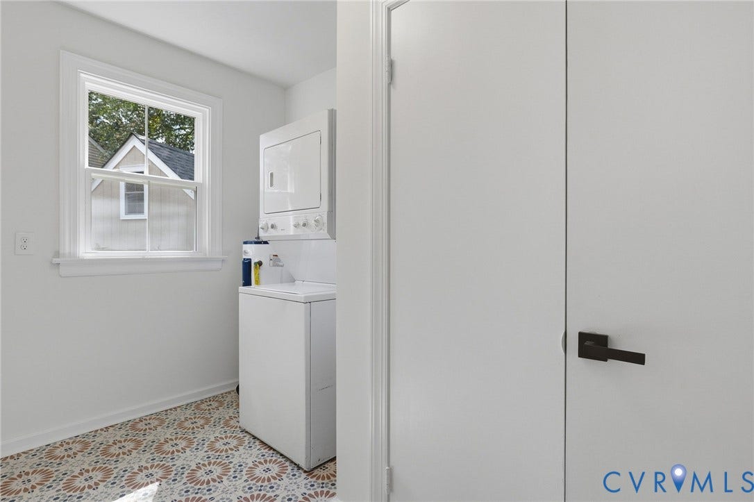 White interior walls, patterned floor tiles, white window trim, and white bi-fold doors with matte black hardware