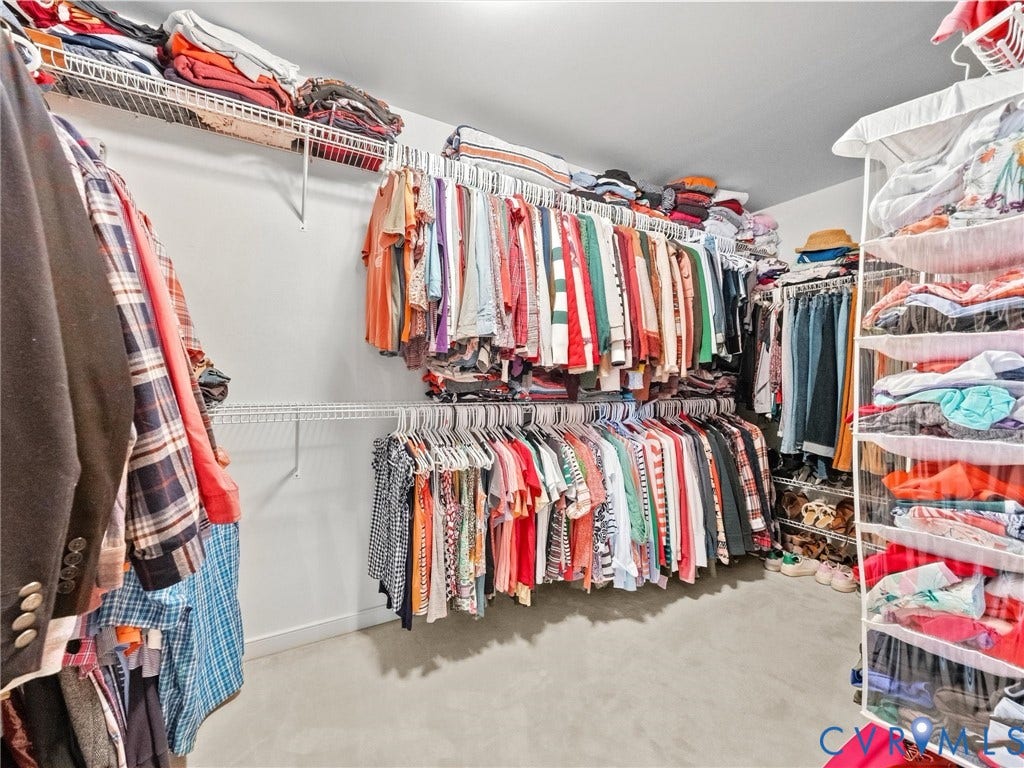 Walk-in closet featuring white wire shelving, multiple hanging rods, and light-colored flooring