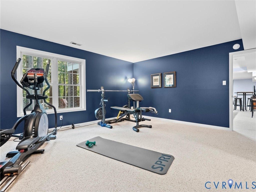 Recessed lighting, light-colored carpeting, and a window with white trim