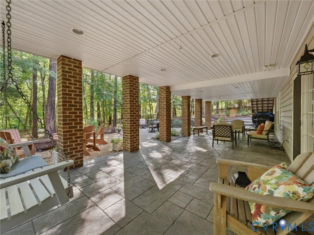 Expansive covered patio featuring brick columns, recessed lighting, white panel ceiling, and stamped concrete flooring