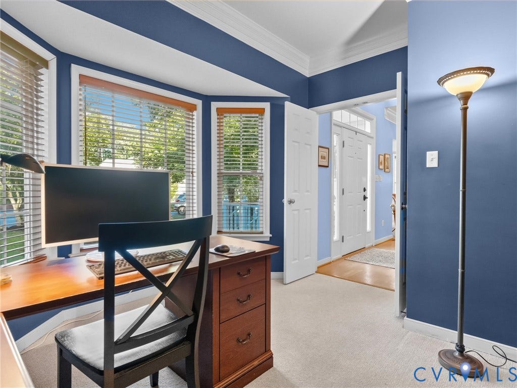 Bay windows with blinds, crown molding, and light-colored carpeting