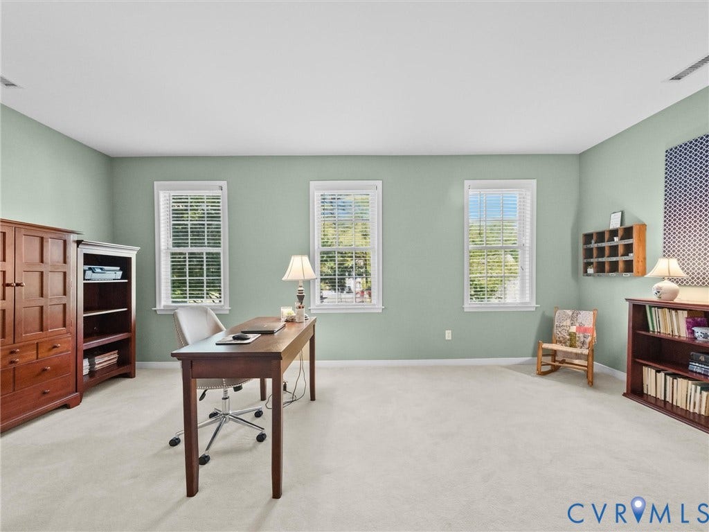 Light green painted walls, three double-hung windows, and light-colored carpeting