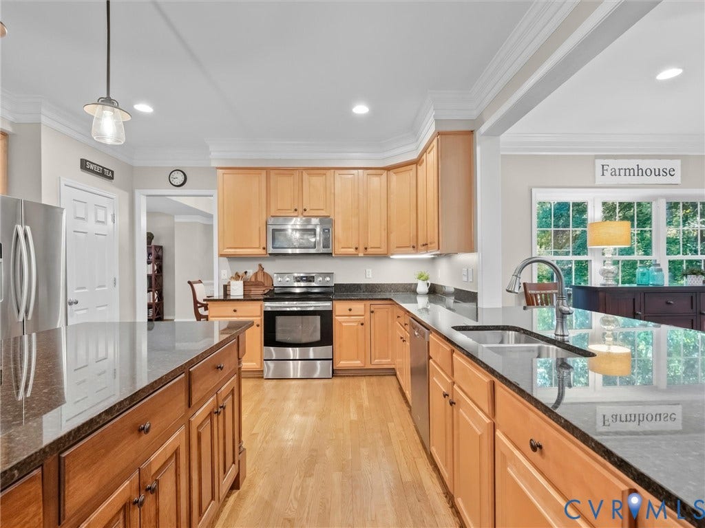 Kitchen featuring wood cabinetry, dark stone countertops, stainless steel appliances, wood-finish flooring, and recessed lighting