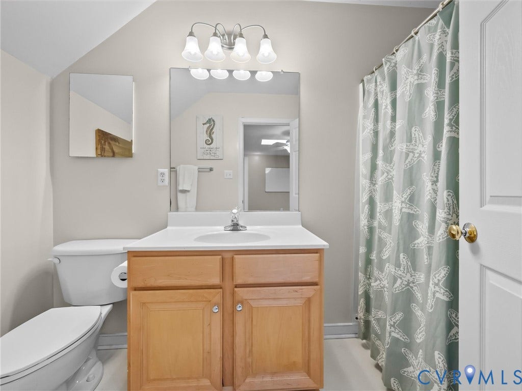 White vanity with a single basin sink, wood-finish cabinetry, and a wall-mounted mirror