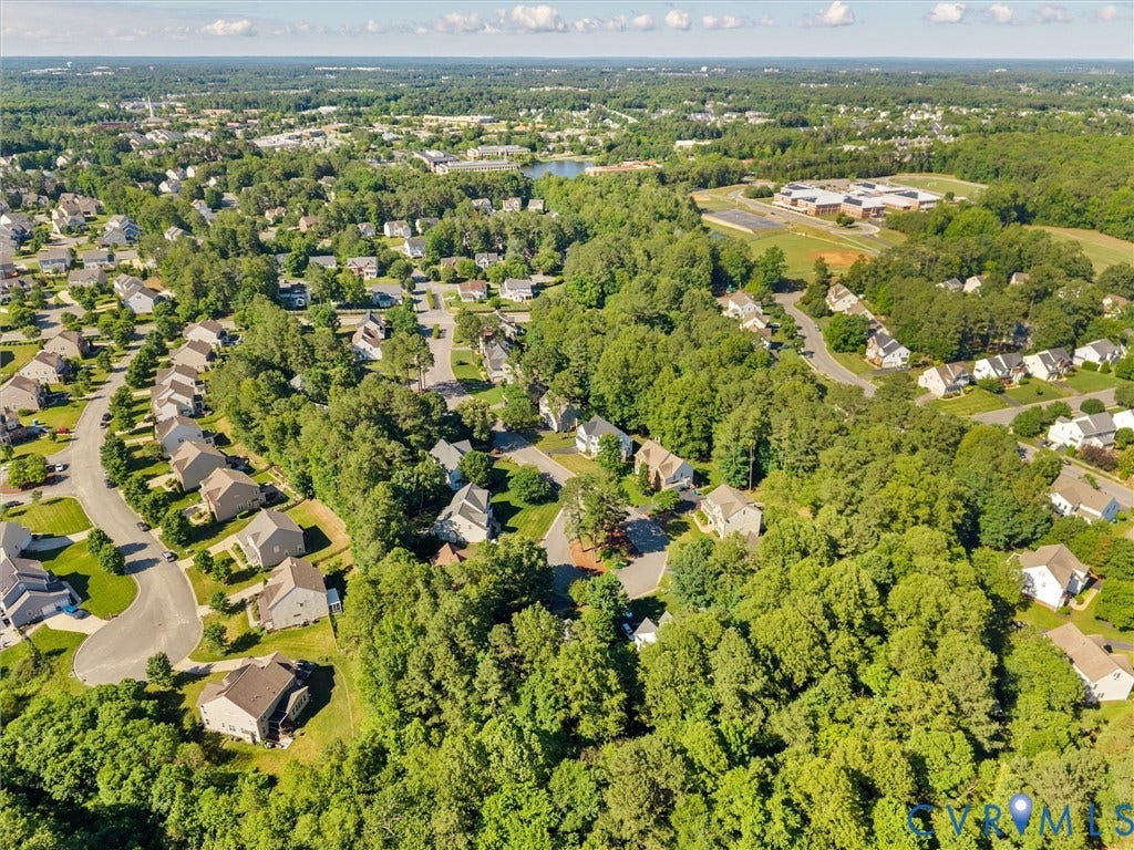 Aerial view showcasing a residential community nestled among mature tree canopy, with tree-lined streets, established landscaping, and neighboring properties visible throughout the expansive neighborhood setting