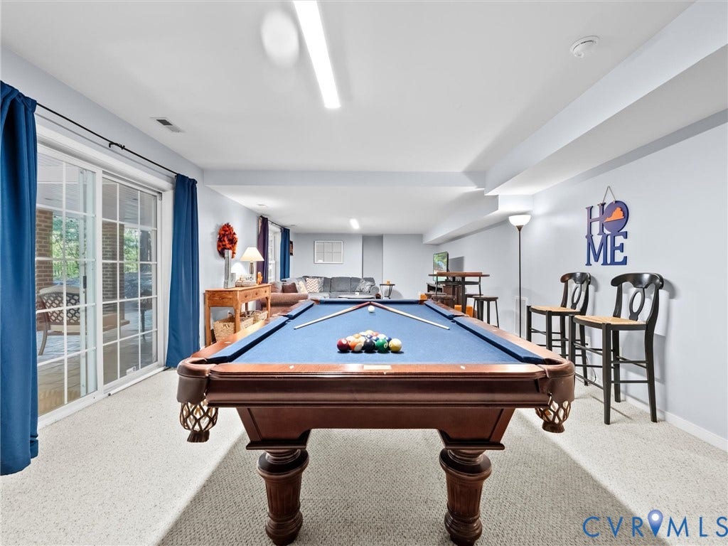 Expansive lower level with light gray walls, plush carpet, and ceiling-mounted lighting