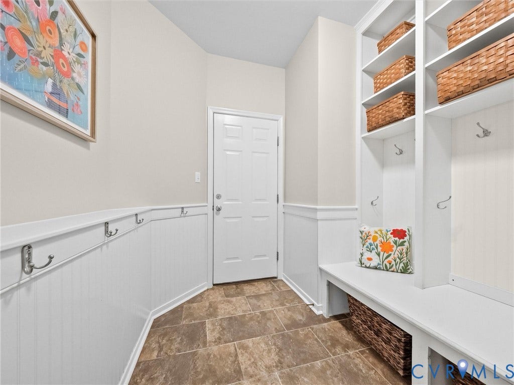 Built-in storage cubbies, storage bench, wall-mounted coat hooks, beadboard wainscoting, and tile flooring