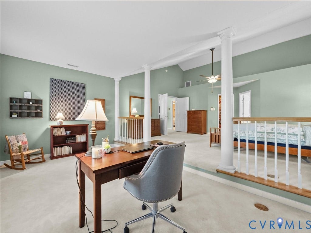Vaulted ceiling with ceiling fan, architectural columns, interior railing, light-toned carpeting, and light green wall color