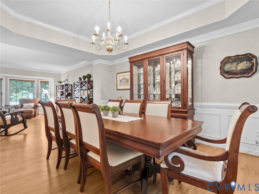 Hardwood flooring, tray ceiling, elegant chandelier, decorative wall molding, and built-in shelving