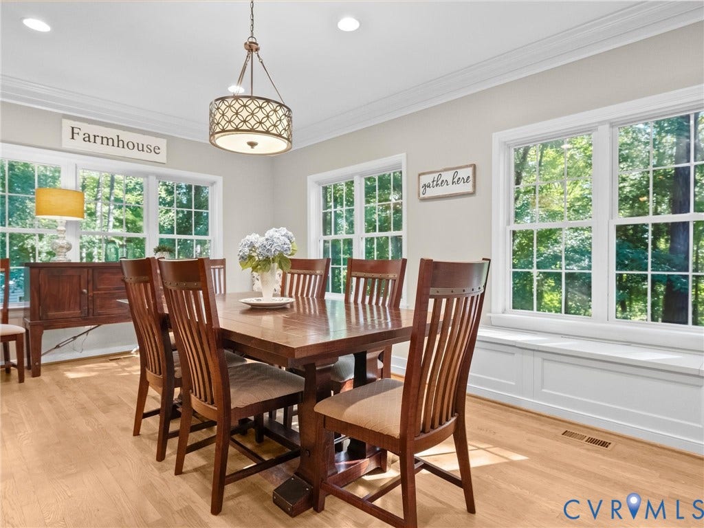 Wood-finish flooring, recessed lighting, crown molding, a built-in window seat, and multiple windows