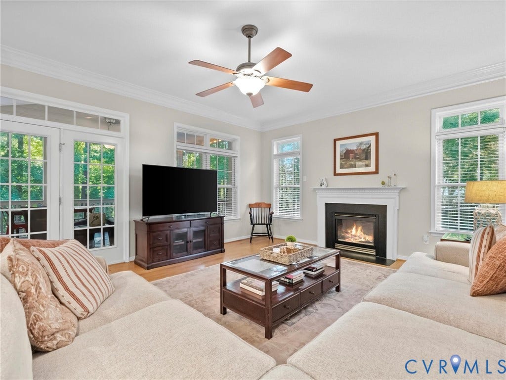 Hardwood flooring, crown molding, a built-in fireplace with mantel, ceiling fan, and French doors