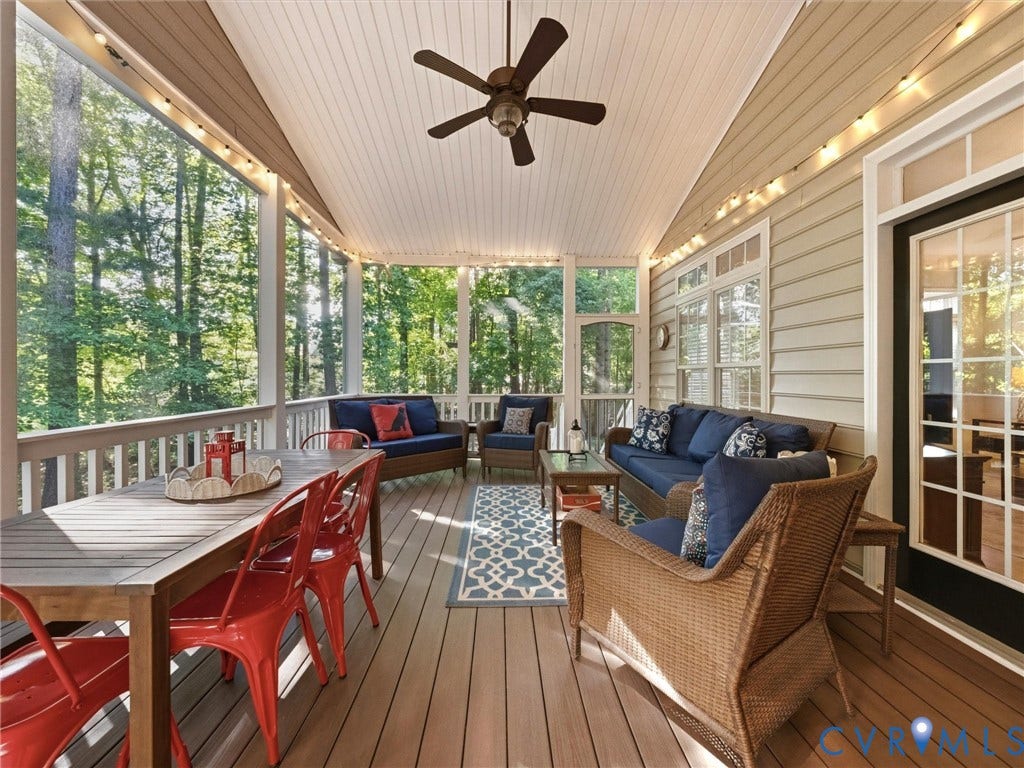 Spacious screened porch featuring a vaulted ceiling with a ceiling fan, composite deck flooring, white railing, and exterior wall siding