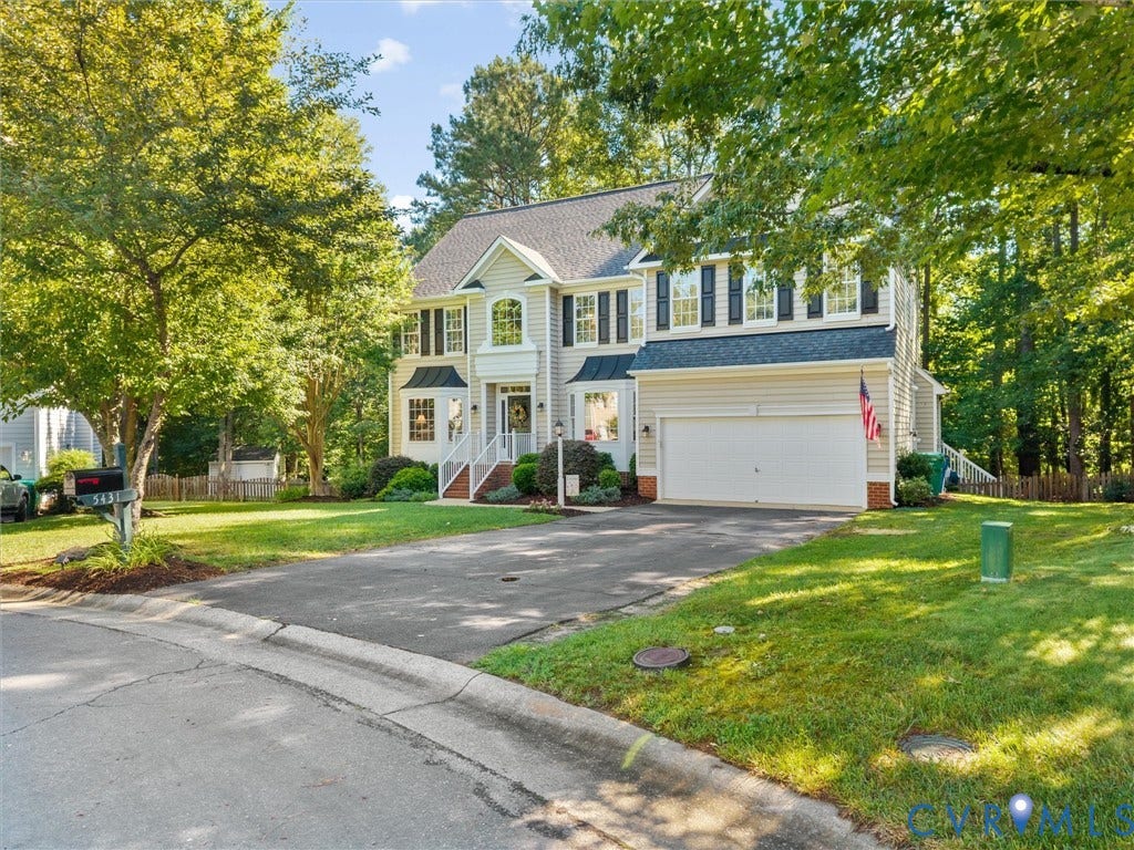 Two-story architectural style with a prominent front entrance, multiple windows with dark shutters, an attached garage, and a paved driveway
