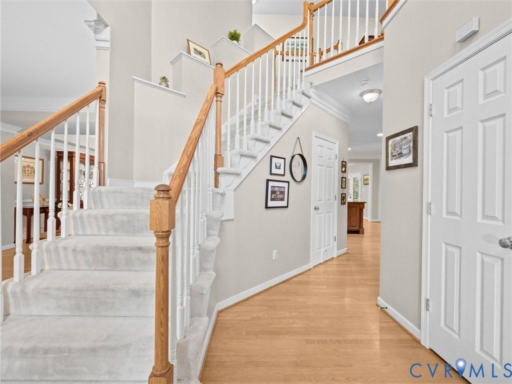 Two-story foyer featuring a carpeted staircase with wood handrails, hardwood flooring, and white panel doors