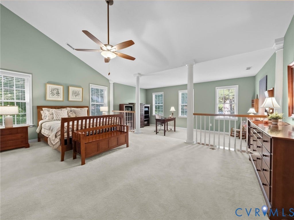 Vaulted ceiling with ceiling fan, multiple windows, carpet flooring, decorative columns, and a white wood railing