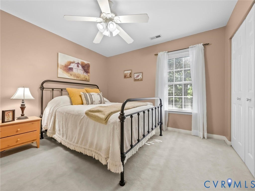 Wall-to-wall carpeting with a multi-pane window, ceiling fan with integrated lighting, and bi-fold closet doors