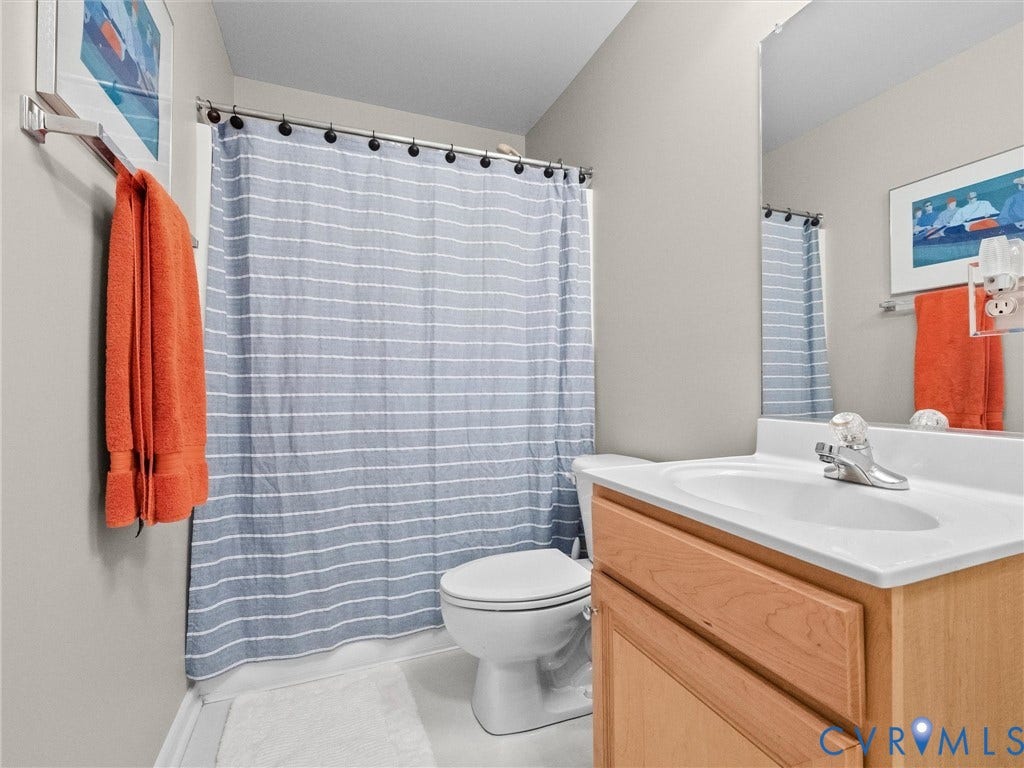 Bathroom featuring a toilet, built-in vanity with integrated sink, and a wall-mounted mirror