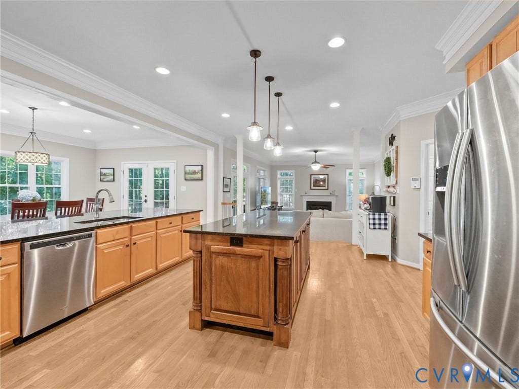 Chef's kitchen featuring wood-finish cabinetry, stainless steel appliances, and a large center island with black countertop seating