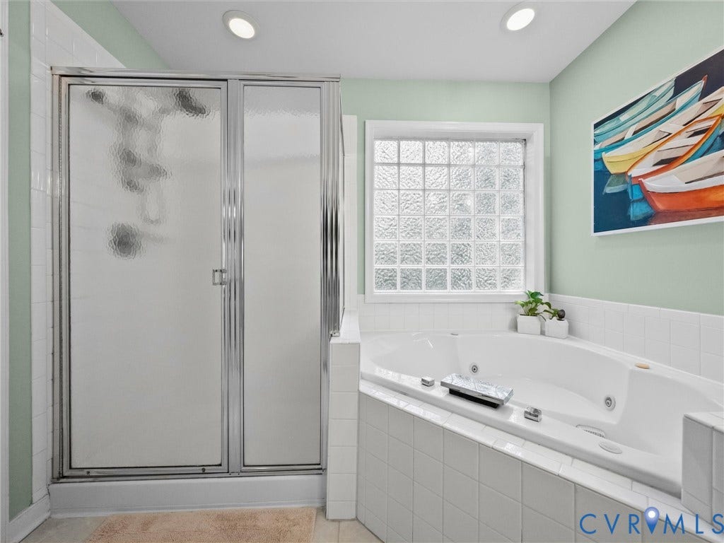 Corner jetted tub with tile surround, glass block window, and separate shower enclosure with frosted glass