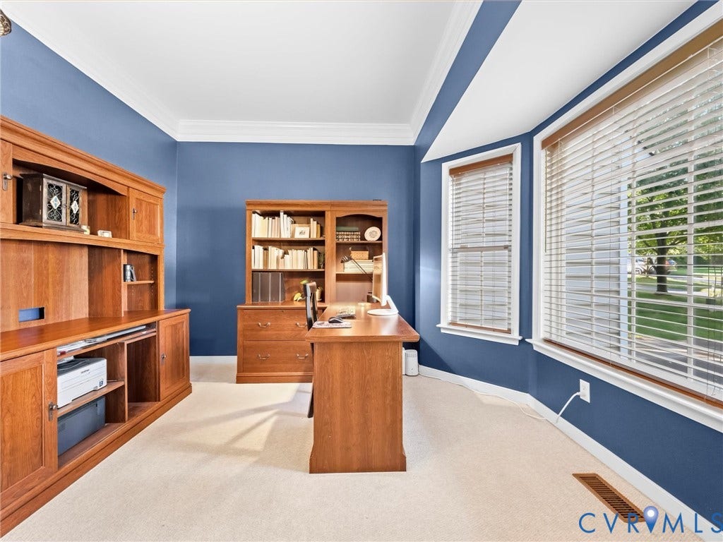 Built-in wood cabinetry, a bay window, crown molding, and carpet flooring