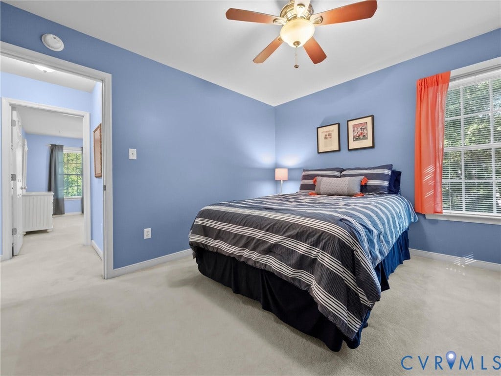 Carpeted room featuring a ceiling fan with light fixture, a window with blinds, and painted walls