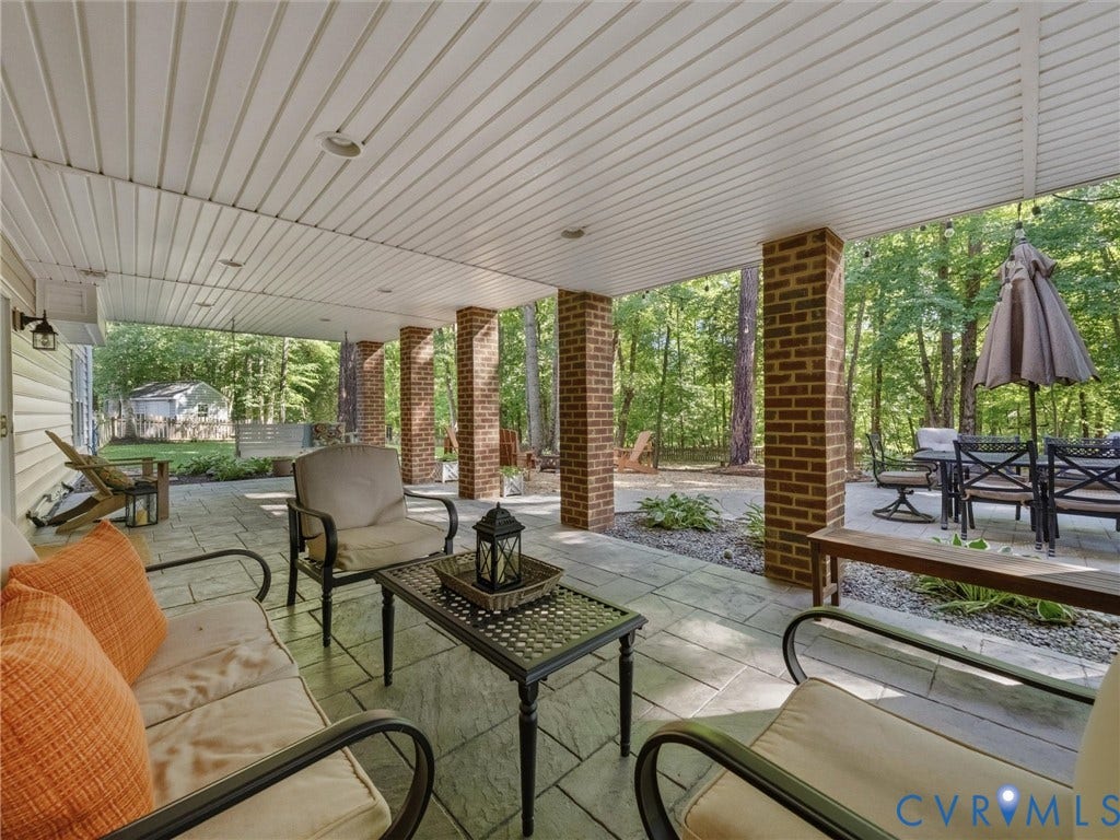 Expansive covered patio featuring brick columns, recessed lighting, and a stone paver surface