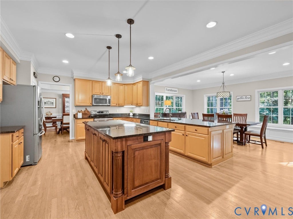 Spacious kitchen with wood-finish flooring, two large kitchen islands, and natural wood cabinetry