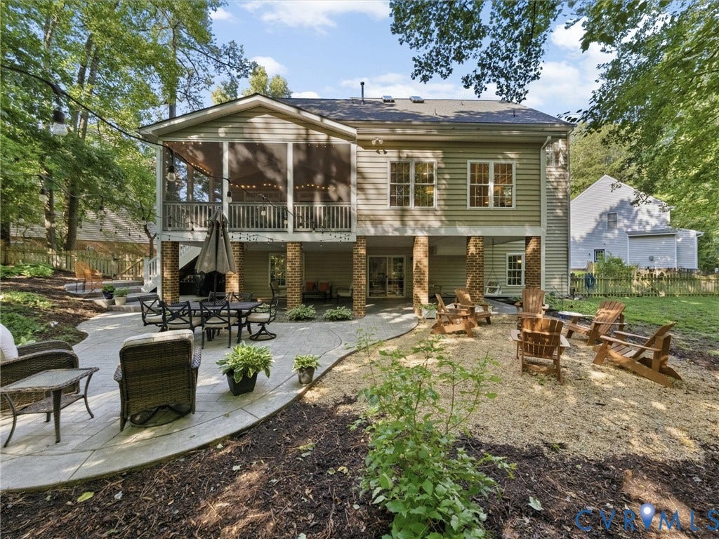 Rear exterior featuring a screened porch, a ground-level patio, and a gravel area