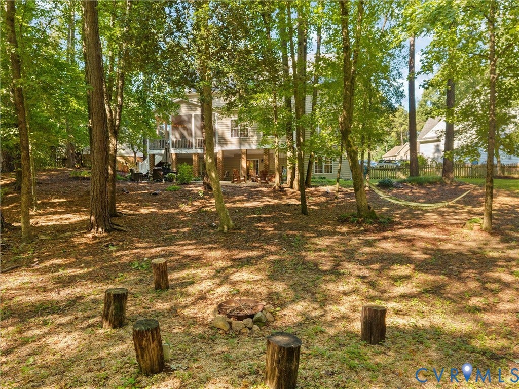 Expansive wooded yard featuring a fire pit, screened-in porch, and a lower-level patio