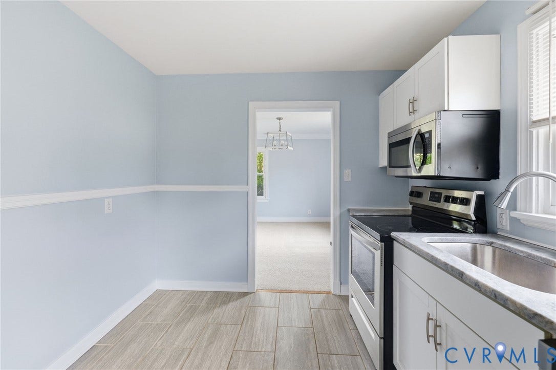 5901 Bonneau Road, Richmond, VA 23227 Ceramic tile flooring, white cabinetry with silver hardware, stainless steel sink, stainless steel microwave, and a black electric range