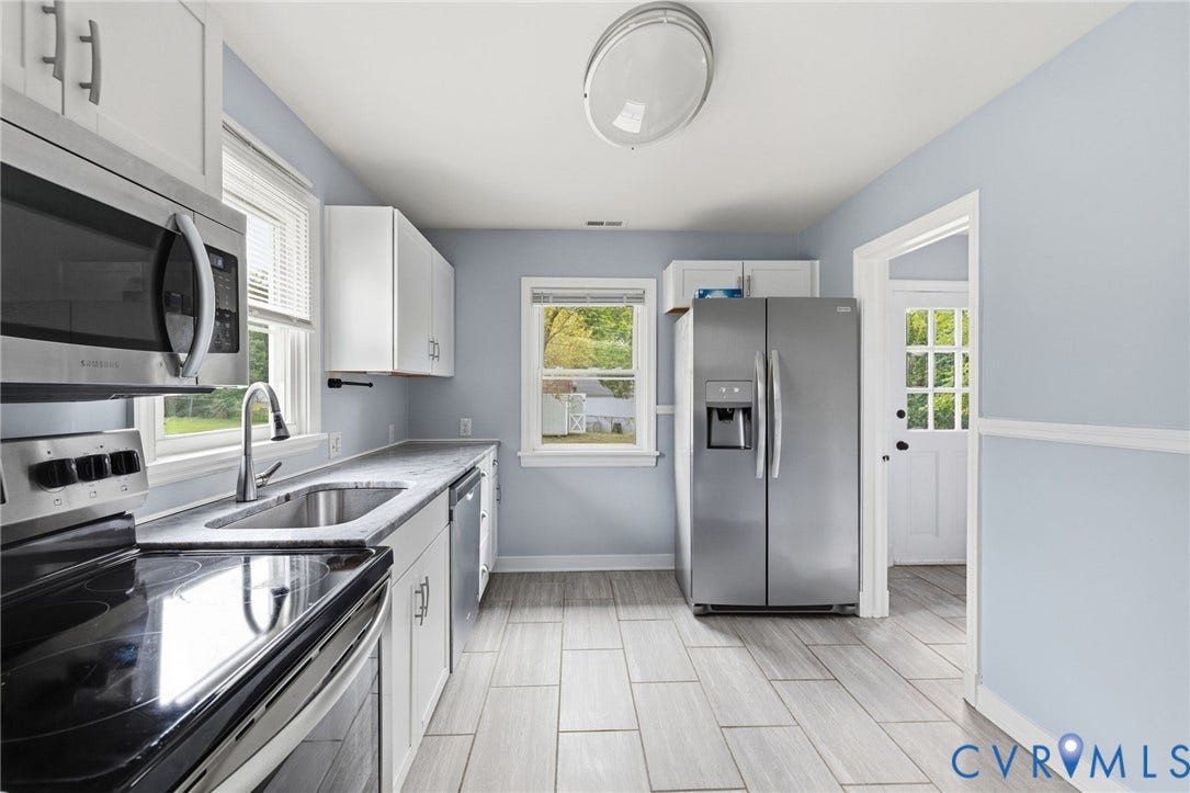 5901 Bonneau Road, Richmond, VA 23227 Updated kitchen featuring white shaker-style cabinetry, stainless steel appliances, a stainless steel sink, and wood-finish tile flooring