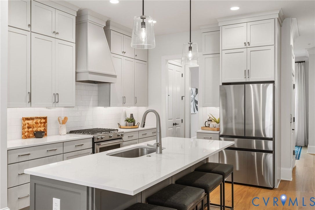 White cabinetry, stainless steel appliances and a contrasting island define the spacious kitchen.