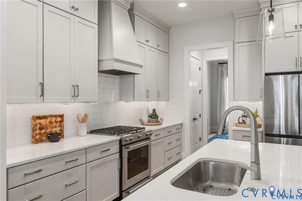 Tile backsplash, generous cabinetry and a statement range hood frame the cooking area.