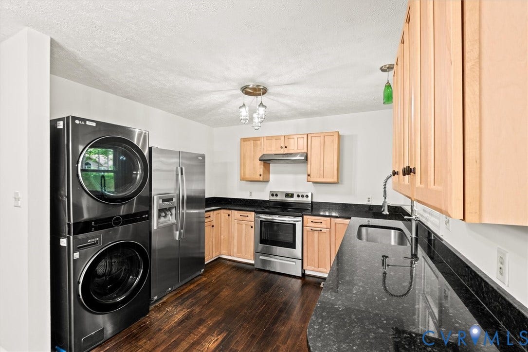 Wood-finish flooring, light wood cabinetry, black granite countertops, stainless steel appliances, and a stainless steel sink with a gooseneck faucet