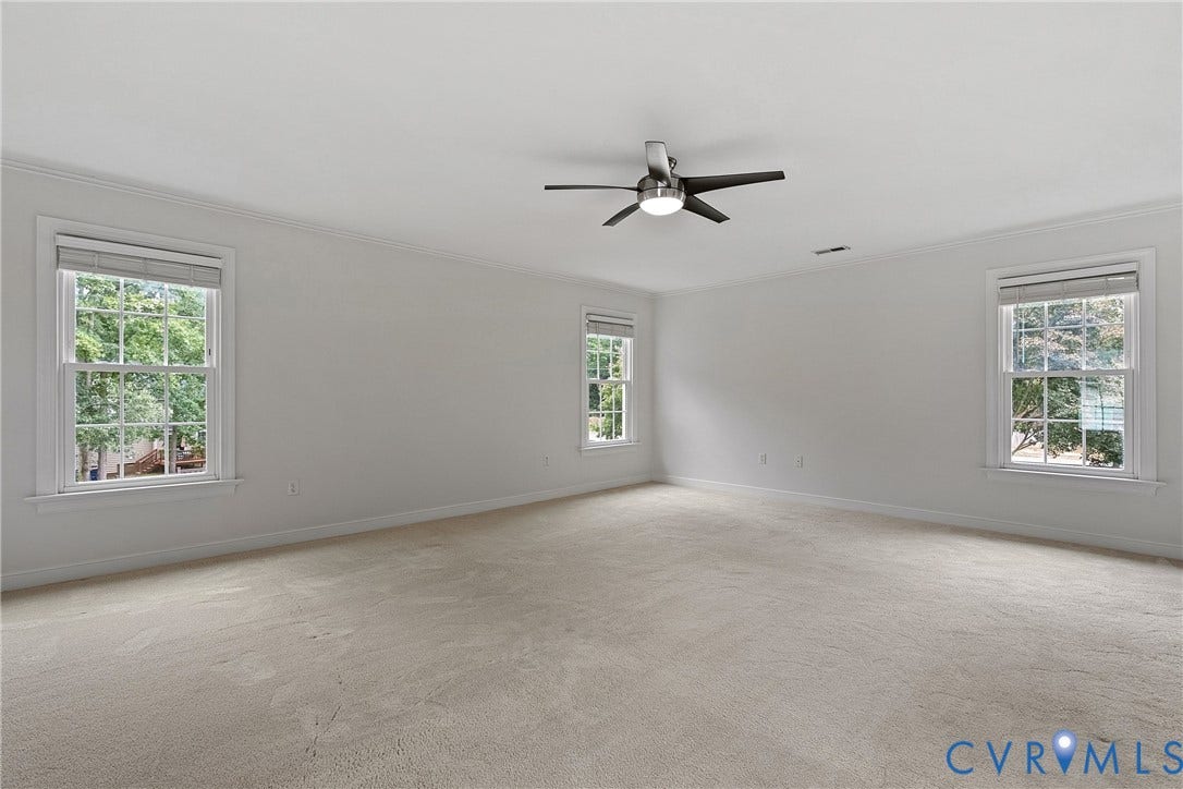 11100 Glen Hollow Court, Henrico, VA 23233 Spacious room with light-colored carpeting, multiple double-hung windows, crown molding, and a ceiling fan with integrated lighting