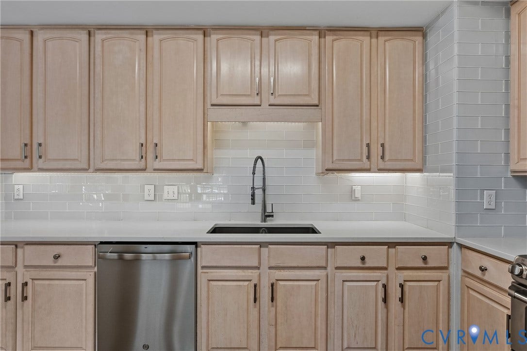 11100 Glen Hollow Court, Henrico, VA 23233 Light-toned cabinetry with dark hardware, a stainless steel dishwasher, a dark basin sink with a gooseneck faucet, light-toned countertops, and a subway tile backsplash