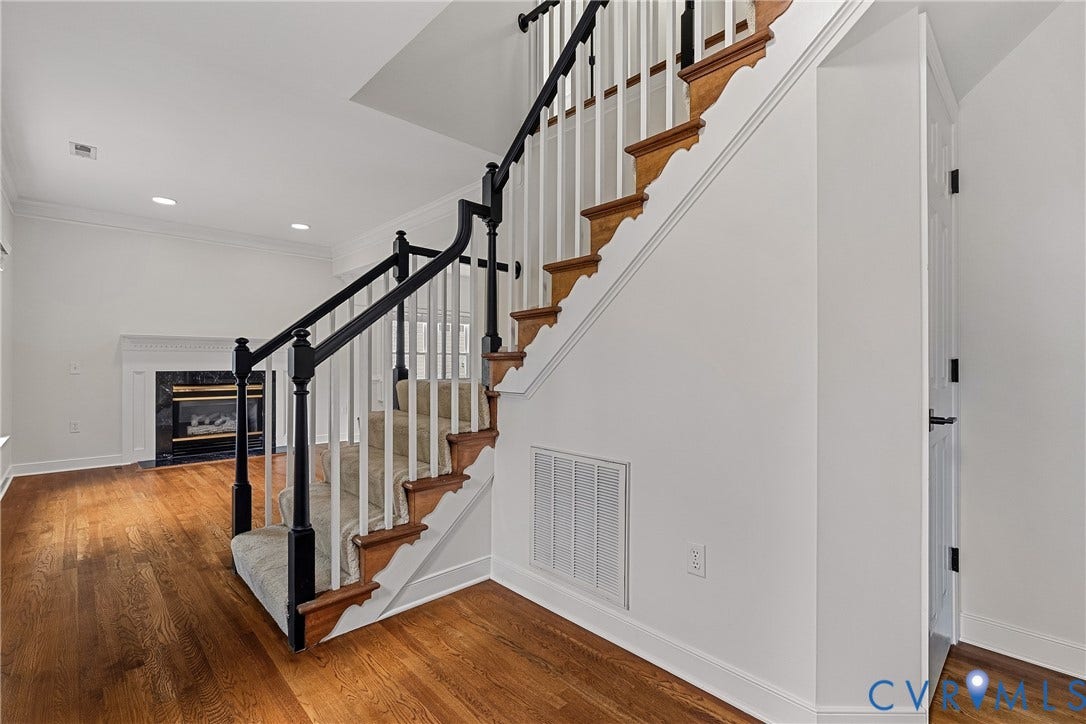 11100 Glen Hollow Court, Henrico, VA 23233 Wood-finish flooring throughout, curved staircase with black newel posts and handrail, carpeted stair runner, and a white fireplace mantel