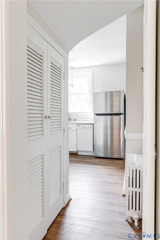 4010 Patterson Avenue, #1stfl, Richmond, VA 23221 Arched doorway leading to a kitchen with stainless steel appliances, white cabinetry, and wood-finish flooring