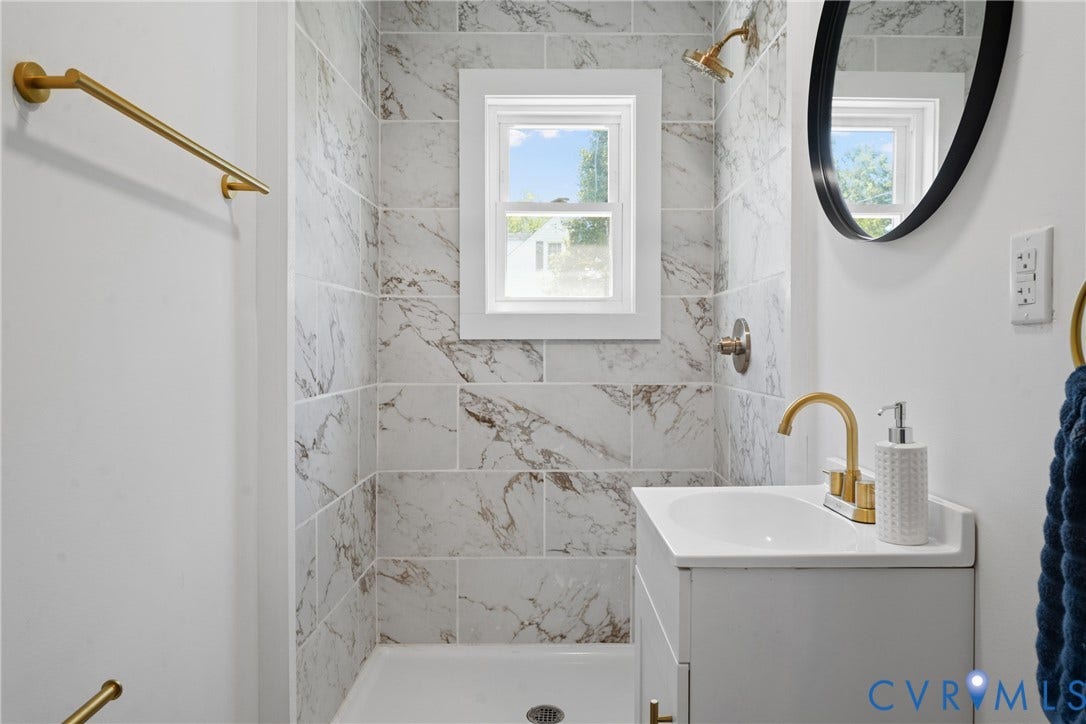 2911 Poplar Street, Hopewell, VA 23860 Shower with tile surround, white framed window, and gold-finish fixtures