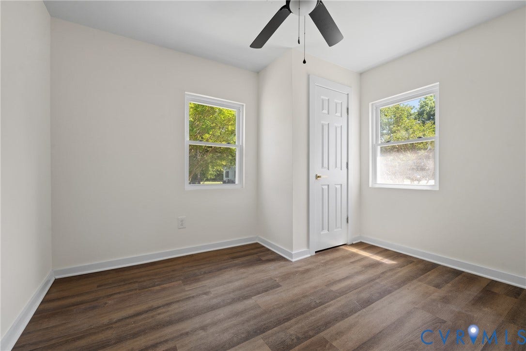2911 Poplar Street, Hopewell, VA 23860 Wood-finish flooring, white walls, two windows with white trim, white paneled door, and a ceiling fan with light fixture