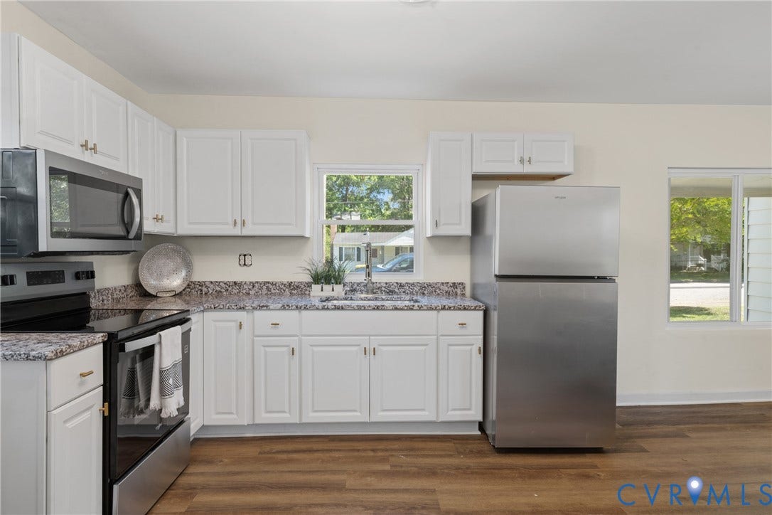 2911 Poplar Street, Hopewell, VA 23860 White cabinetry, granite-finish countertops, stainless steel appliances, wood-finish flooring, and a large window