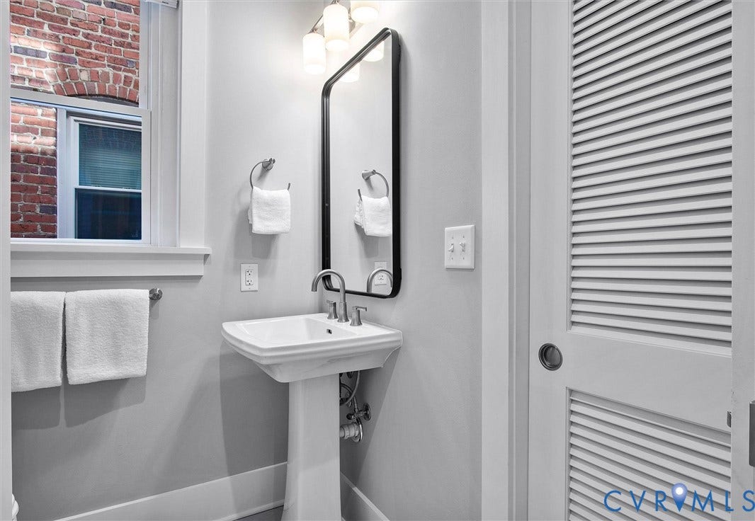 2902 Idlewood, #5, Richmond, VA 23221 Pedestal sink with chrome faucet, black-framed mirror, and a three-light vanity fixture