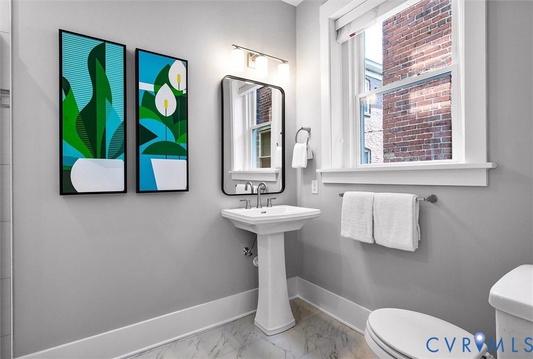 2902 Idlewood, #5, Richmond, VA 23221 Pedestal sink with polished chrome faucet, framed vanity mirror, and wall-mounted light fixture