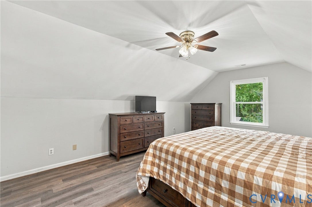 Room with wood-finish flooring, vaulted ceilings, and a ceiling fan with integrated lighting