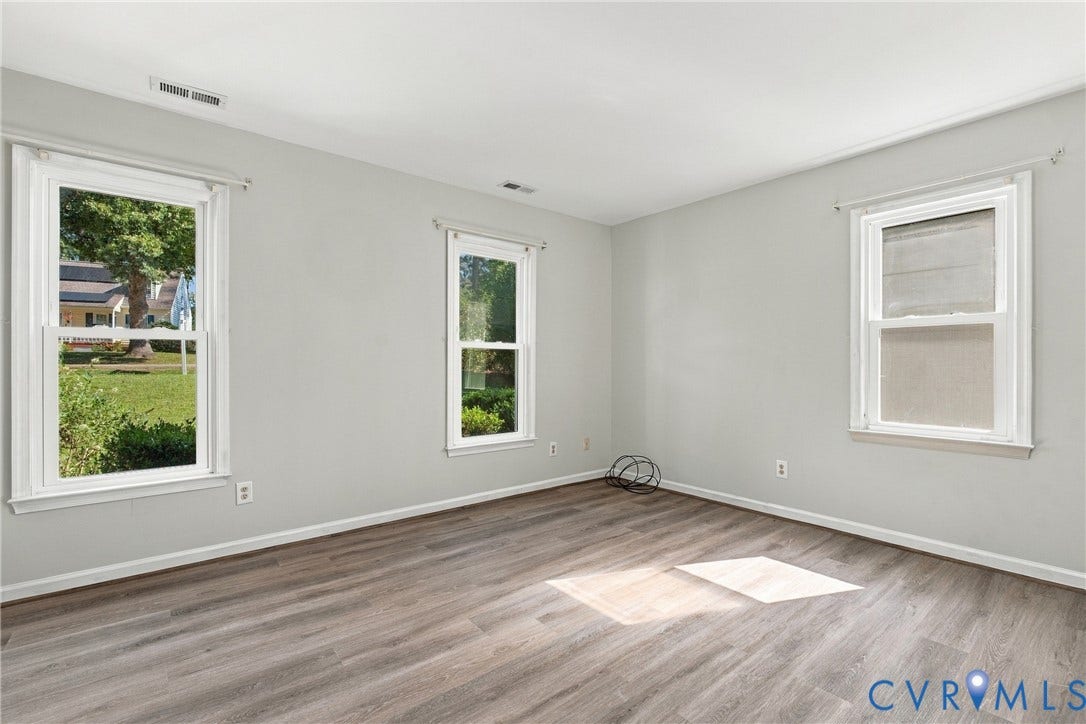 Neutral-toned walls and wood-finish flooring featuring triple double-hung windows
