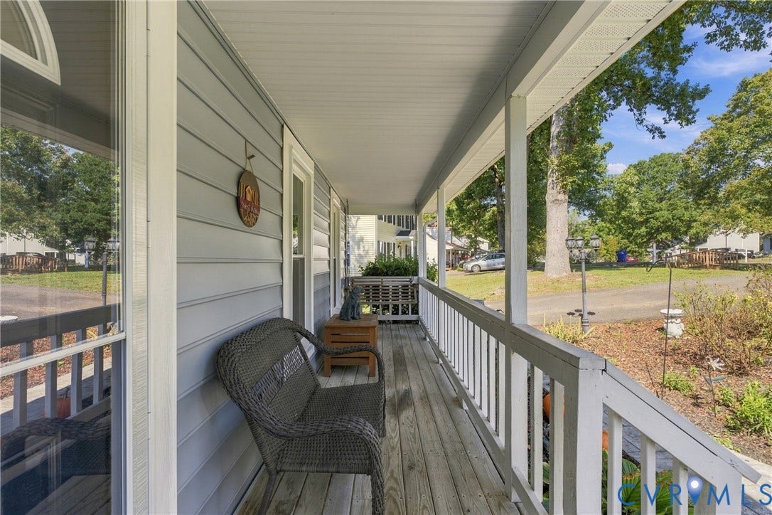 Covered front porch featuring wood-plank decking, white railings, and horizontal siding