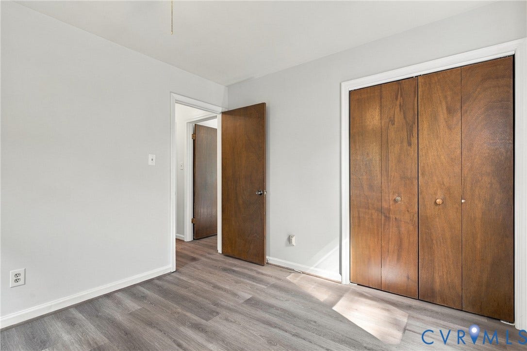 Wood-finish flooring, neutral wall paint, bi-fold wooden closet doors, and traditional wooden interior doors