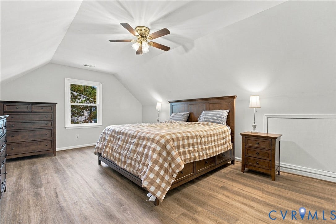Vaulted ceilings with a multi-blade ceiling fan and wood-finish flooring